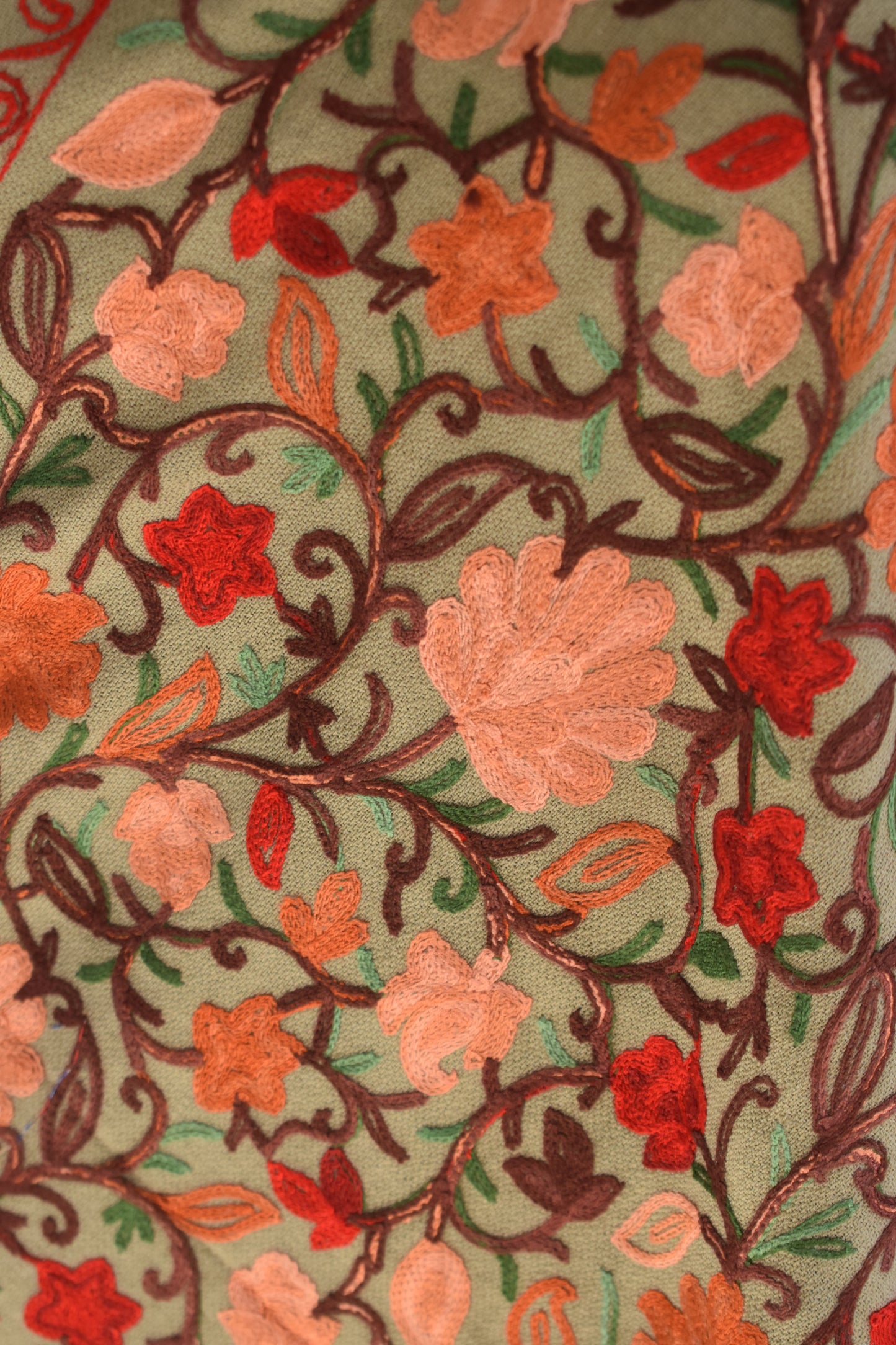 Close-up of aari floral embroidery on stole with red, pink, and orange flowers.