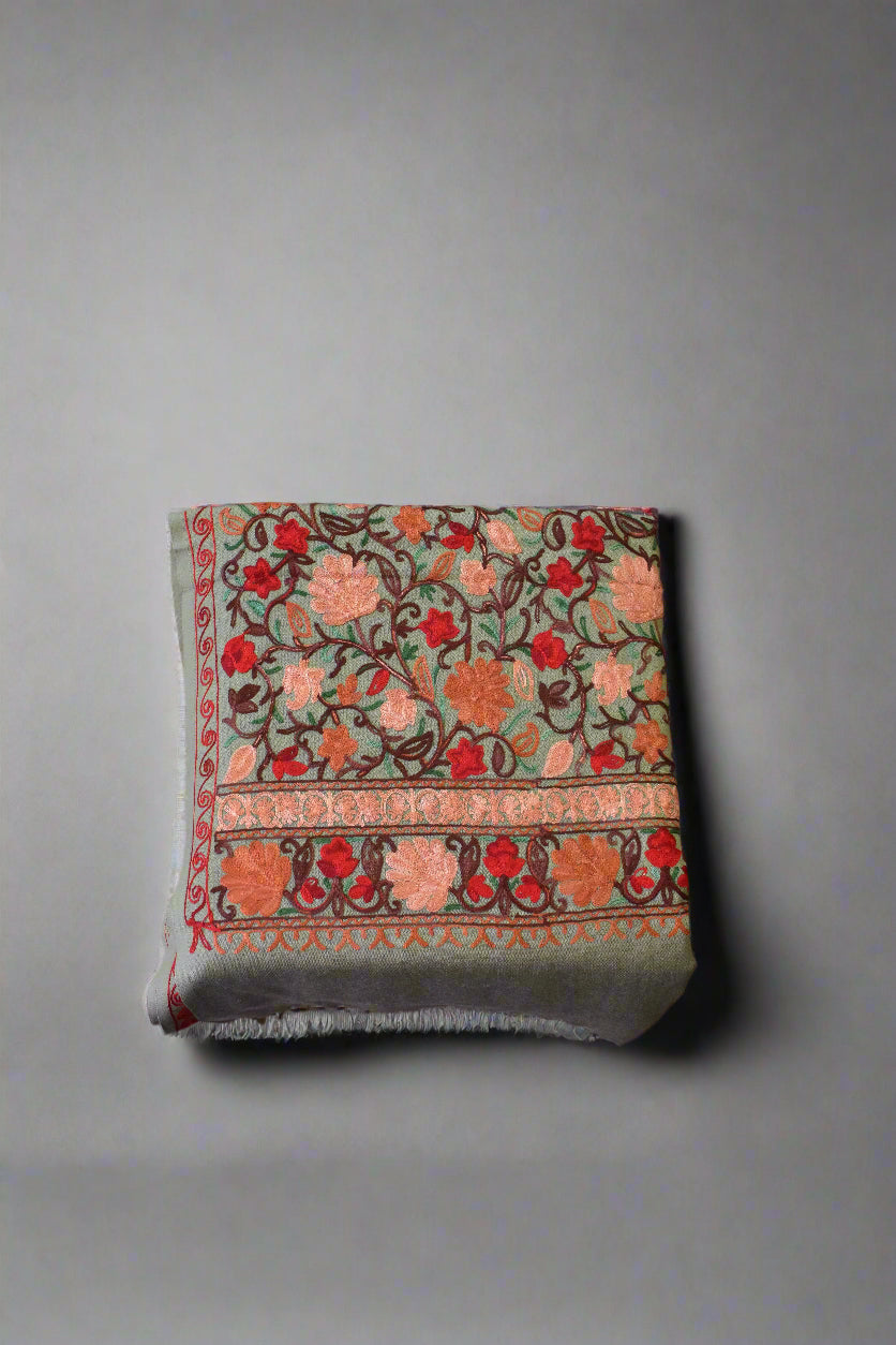 Decorative floral-patterned aari stole on a wooden floor