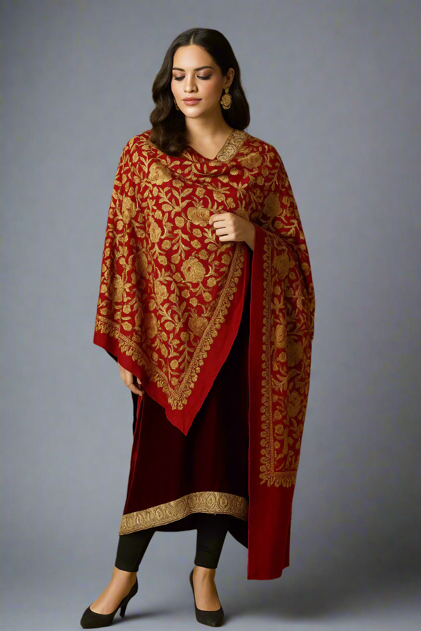 Woman wearing a red and gold traditional outfit with a matching shawl against a brown background