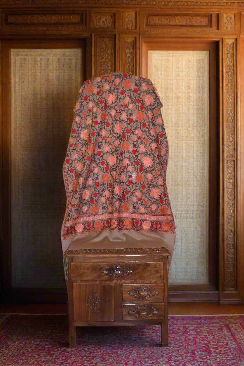 Floral-patterned aari stole on a wooden surface with a neutral background
