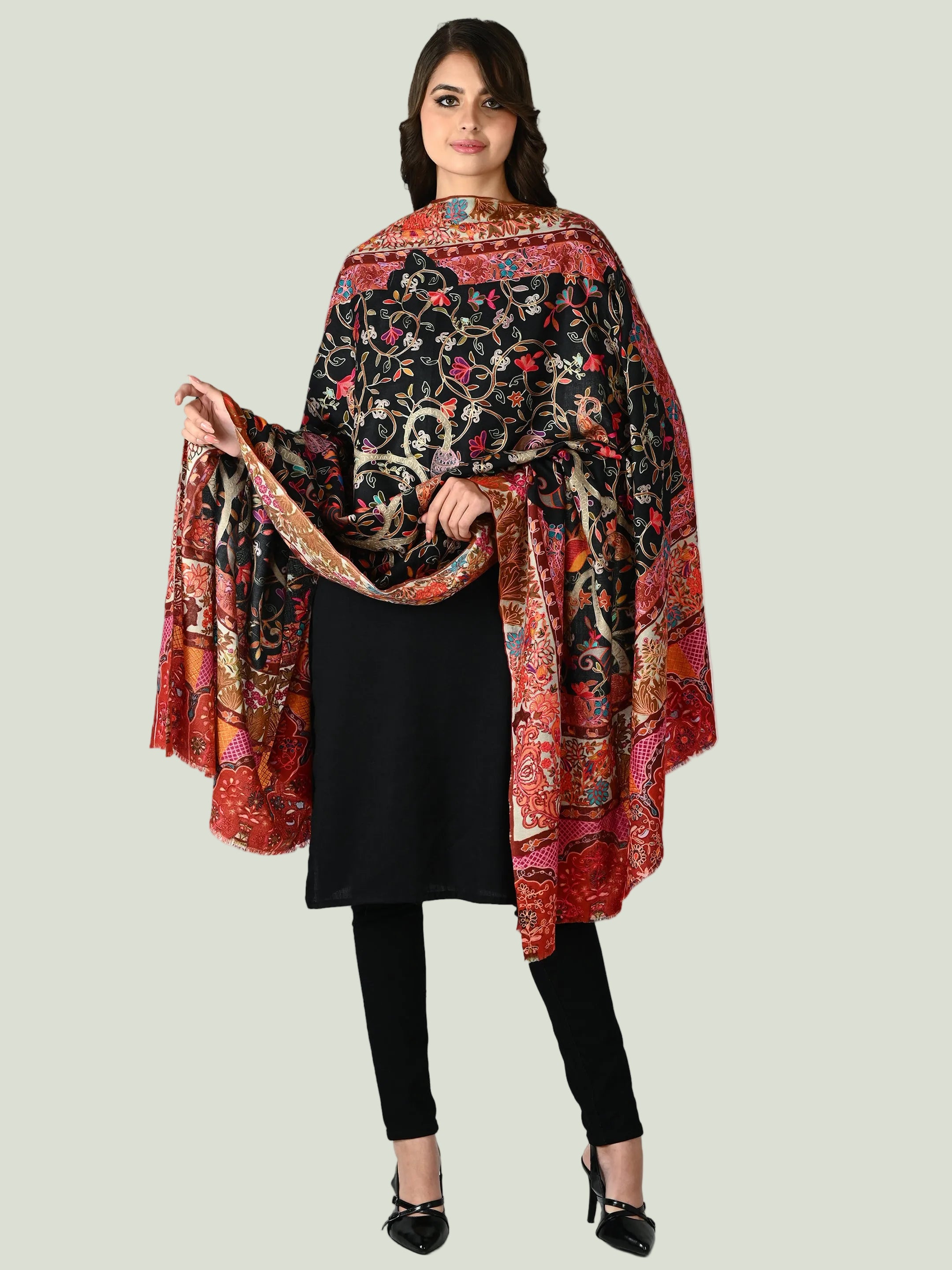 Woman wearing a colorful Paisley Couture shawl over a black outfit on a white background